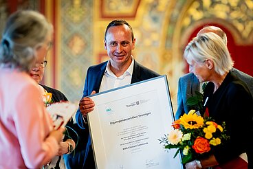 Vertreter des KMG Klinikums Sömmerda mit einer großen eingerahmten Urkunde
