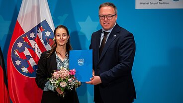 Staatssekretärin Tina Rudolph neben Ministerpräsident Mario Voigt. In den Händen hält sie die Ernennungsurkunde.